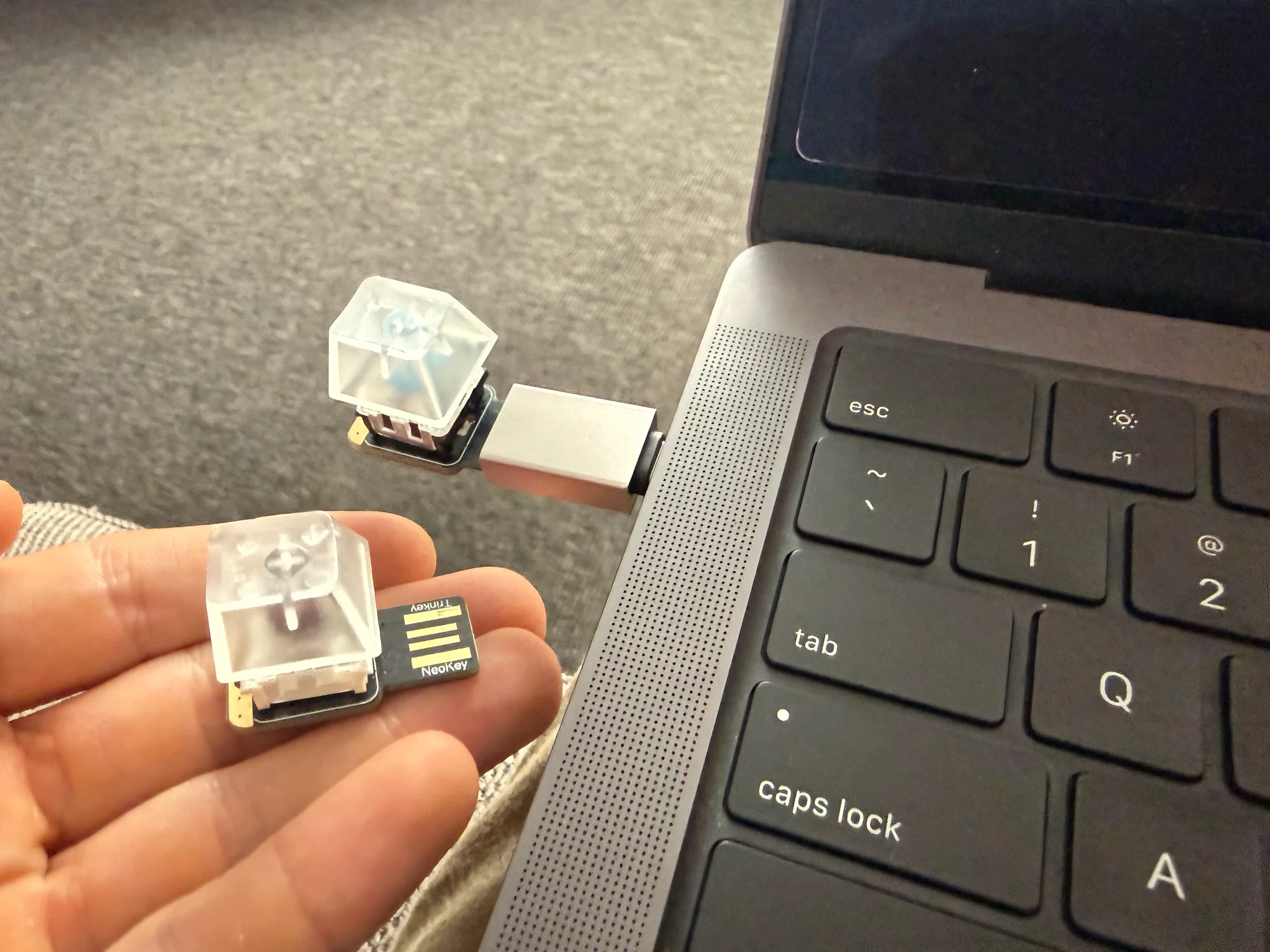 Two Singlet prototypes with clear keycaps, one plugged into a laptop and one held in a hand.